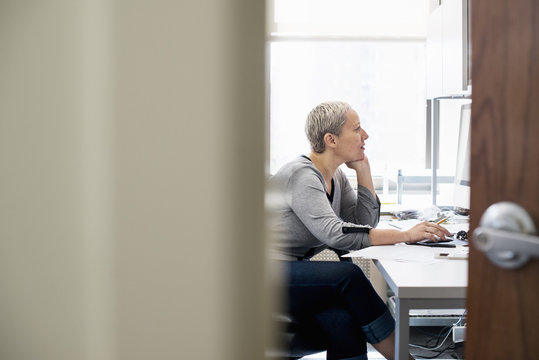 A woman working in an office alone. Focusing on a task, using a computer.