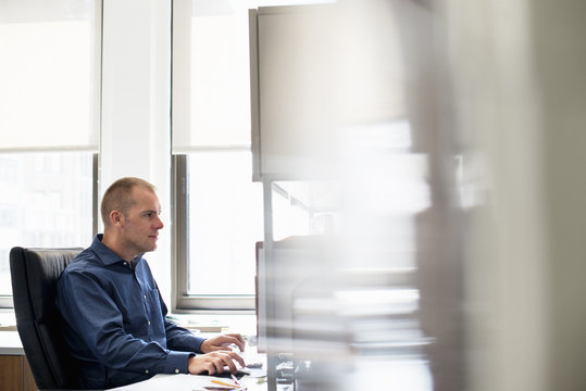 A man working in an office at a desk using a computer mouse. Focusing on a task.