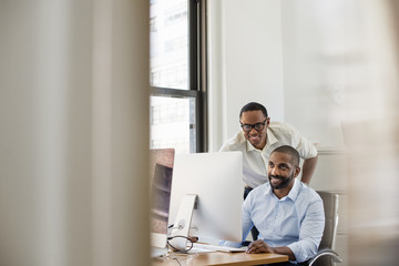 Two men looking at a computer screen in an office.