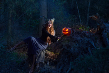 Beautiful witch with a pumpkin in the magic forest
