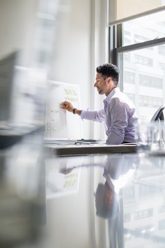 Office life. A man working on a wall chart in his office.