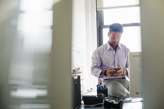 Office life. A man checking his phone in an office.