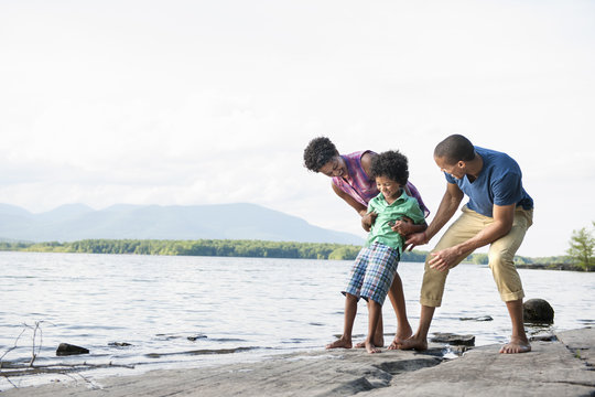 A family, mother, father and son playing on the shores of a lake.