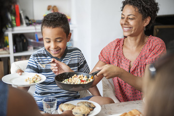 A family gathering for a meal. Adults and children around a table.