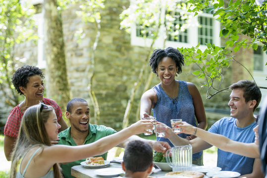 A family gathering; men women and children around a table in a garden in summer.