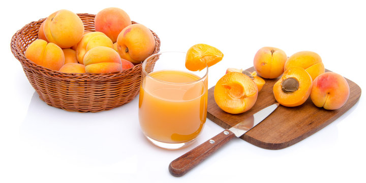 Glass of apricot juice with a basket of apricots and sliced apri
