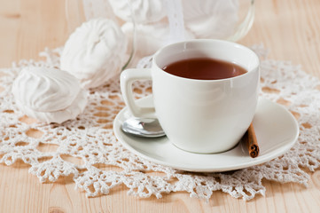 Cup of tea with cinnamon and marshmallows on the lace napkin