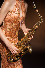 Sexual young woman posing with saxophone at studio