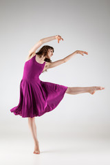 Young ballet dancer wearing purple dress over grey