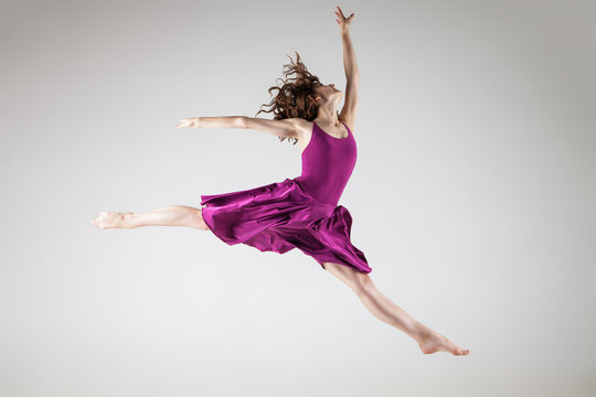 Young ballet dancer wearing purple dress over grey