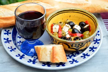 Foto auf Glas Een schaaltje olijven met stokbrood en rode wijn. © trinetuzun