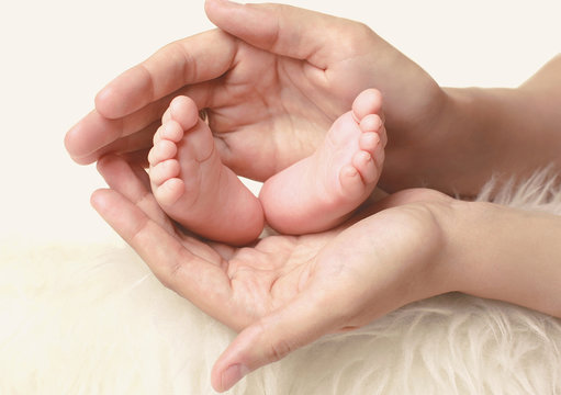 Newborn baby feet in mother's hands on a white background