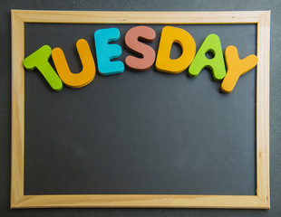 Colorful wooden word Tuesday on black board