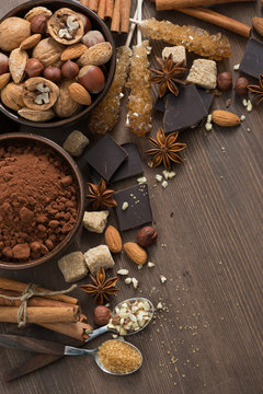 cocoa, chocolate, nuts and spices on wooden background, vertical