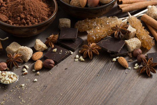 cocoa, chocolate, nuts and spices on wooden background