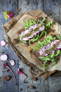 rye bread with rocket, radish slices, anchovies and seed