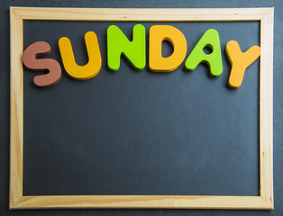 Colorful wooden word Sunday on black board