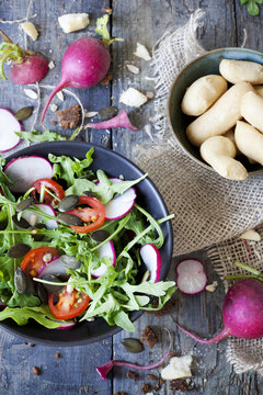 rocket salad on bowl with radish, tomatoes, seed,  bread sticks