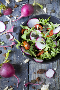 rocket salad on bowl with radish, tomatoes and seeds