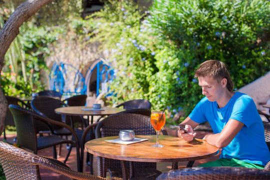 Young man in outdoor cafe talking on phone