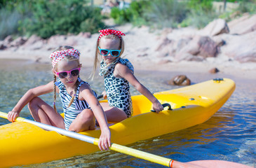 Little adorable girls enjoying kayaking on yellow kayak in the