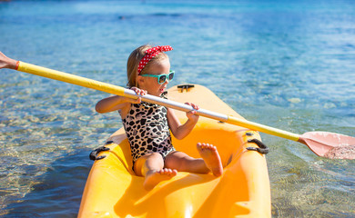 Little cute girl enjoy swimming on yellow kayak in clear