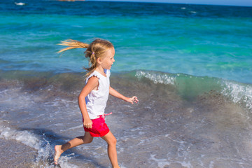 Adorable little girl playing at white beach during tropical