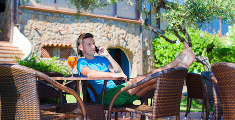 Young man in outdoor cafe talking on phone