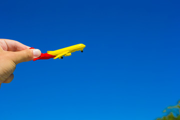Small plane in female hand on background of blue sky