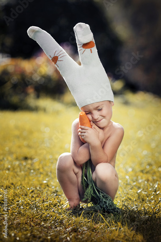 cute boy dressed as a bunny with fresh carrots in hands