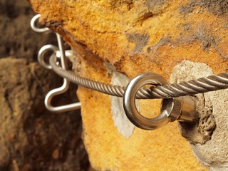 Detail of thin iron rope end anchored for climbers into rock
