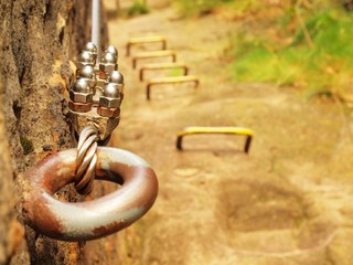Detail of thin iron rope end anchored for climbers into rock