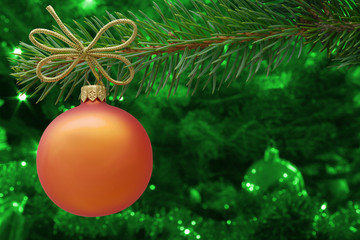 Christmas bauble and spruce branch on green background