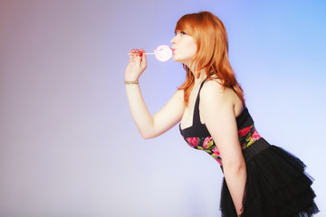 Redhair girl holding sweet food lollipop candy on blue.