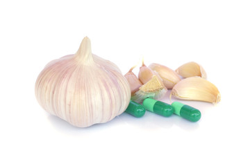Herbal pills and garlic on a light colored background