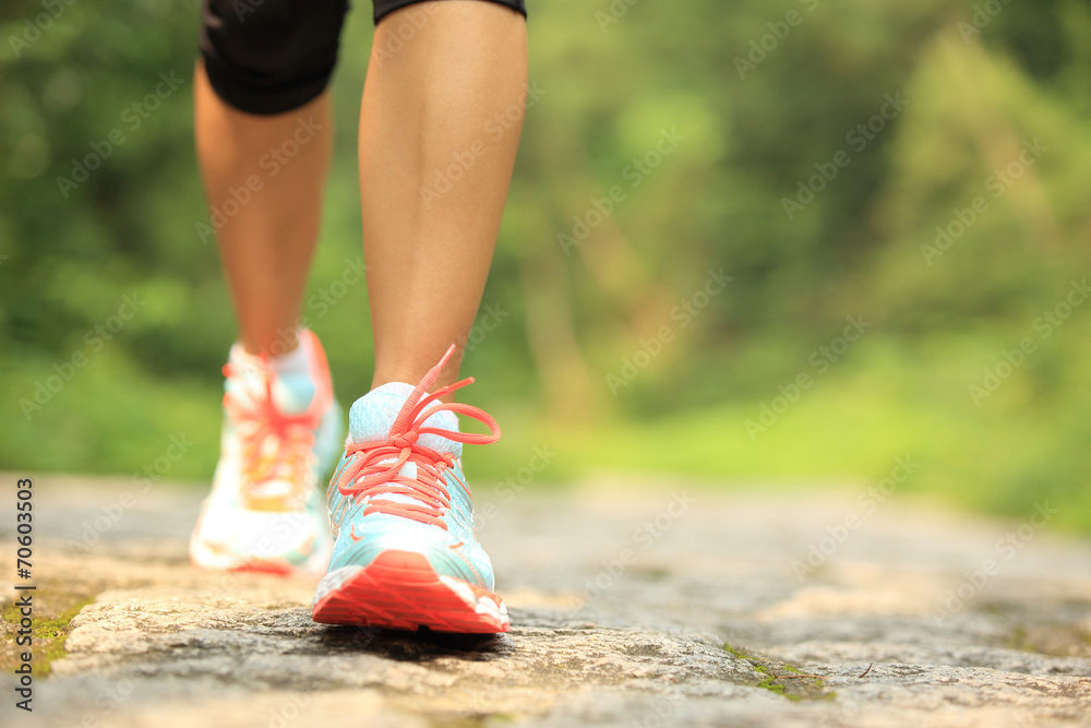 Wall mural young fitness woman legs walking on forest trail