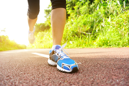 young fitness woman legs running on forest trail