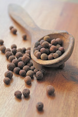 Old wooden spoon with aromatic allspice peppers