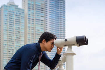 Fototapeta na wymiar Asian business man with binoculars looking at city
