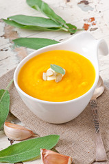 Cream of pumpkin soup with sour cream sauce decorated with a lea