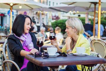 Two women drinking wine and having friendly chat in restaurant