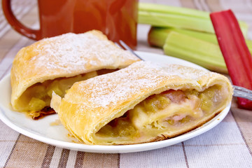 Strudel with rhubarb and mug on linen tablecloth