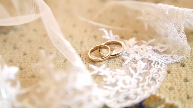 Two gold wedding rings on a white veil of the bride.