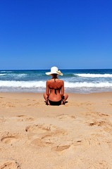 woman with hat watching the sea