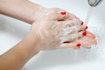Close up of hands with soap lather over bathroom sink