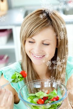 Young woman eating a salad in the kitchen