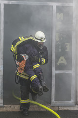 Fototapeta premium Feuerwehrmann rettet Person aus brennendem Gebäude