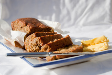 Half cut banana bread loaf on platter on white cloth