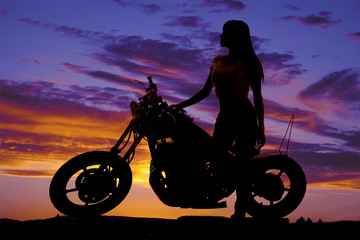 Fototapeta na wymiar silhouette of a woman standing by a motorcycle looking forward