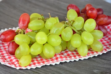 Tapeten tros rode en groene druiven op een geruit kleedje © trinetuzun